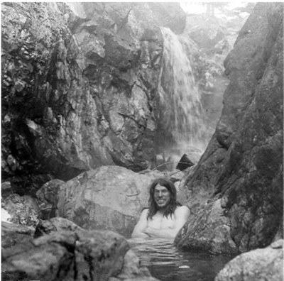 artist sitting in hotsprings below hot waterfall